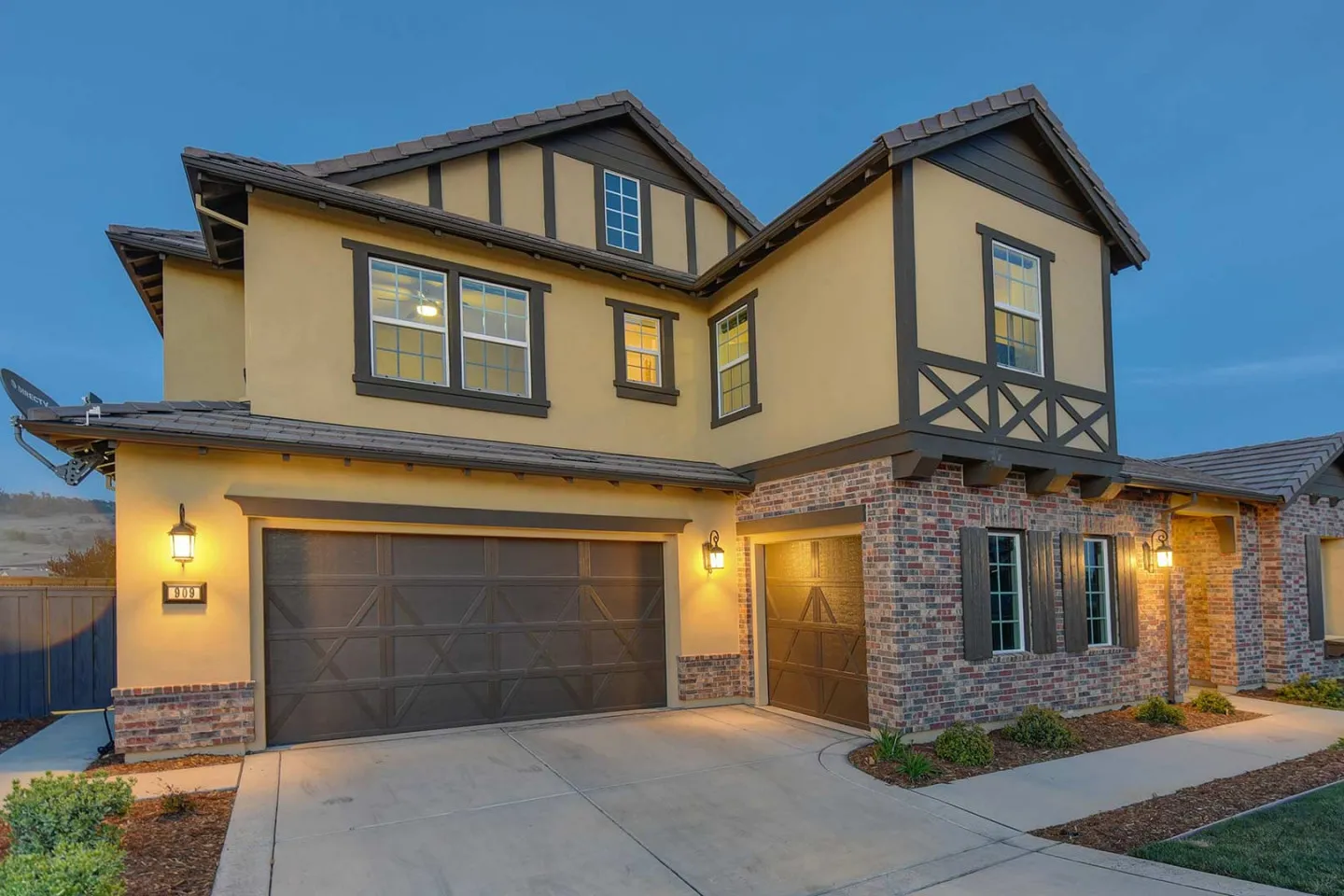 Two-story stucco and brick home at dusk with warm window lights (illustrative)
